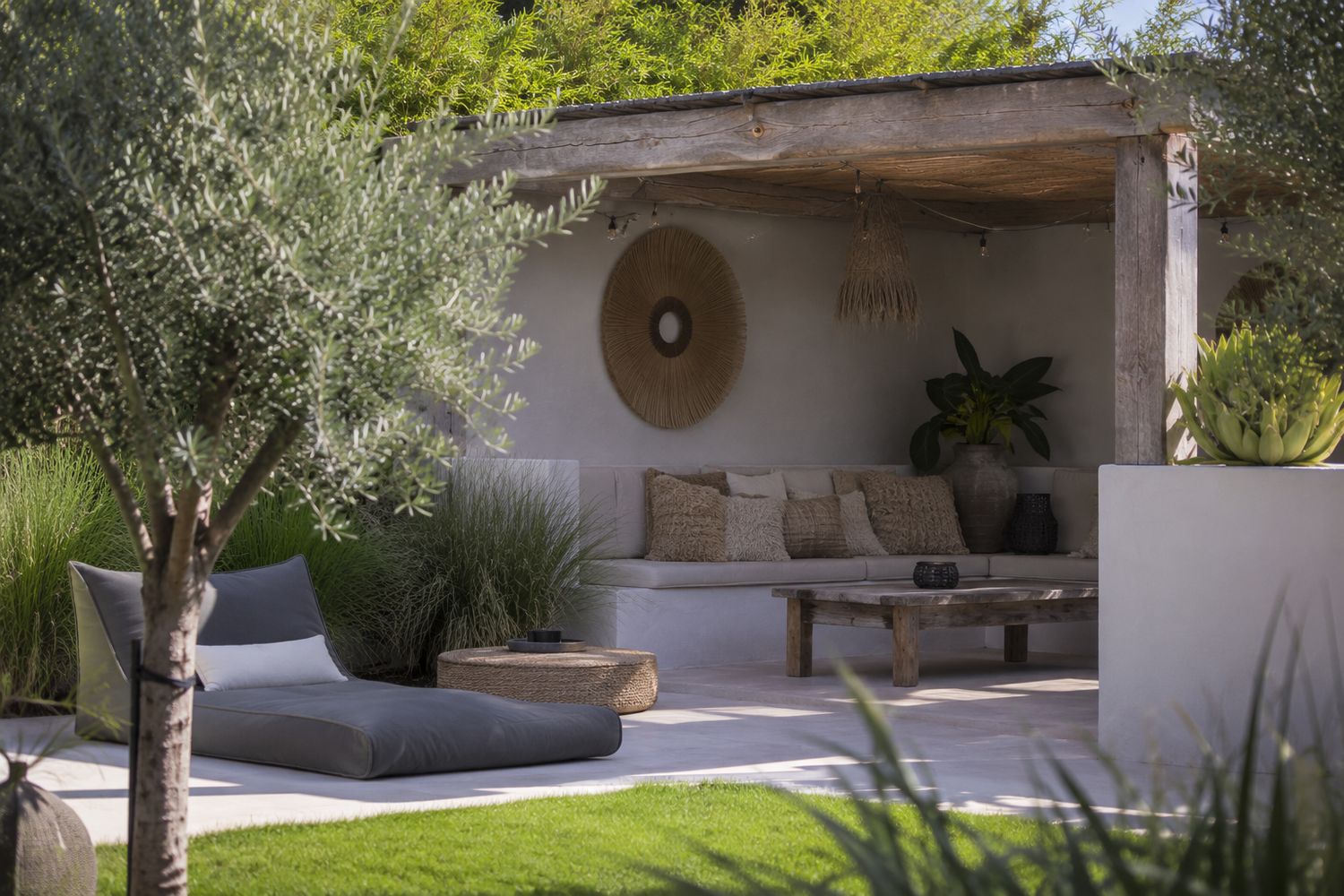 Terras in Ibiza-stijl met witte muur, rieten scherm en olijfboom in terracotta pot